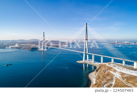 Stunning view of the Russky Bridge in Vladivostok with clear blue skies and tranquil waters. Stunning view of the Russky Bridge in Vladivostok with clear blue skies and tranquil waters. 124507465