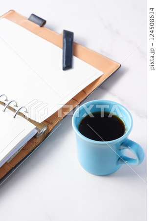 淹れたてのコーヒーを飲みながら、リング式のシステム手帳を開いてデスクワークをしているイメージ 124508614