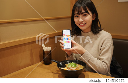 ラーメン屋でスマホを操作する女の子 124510471