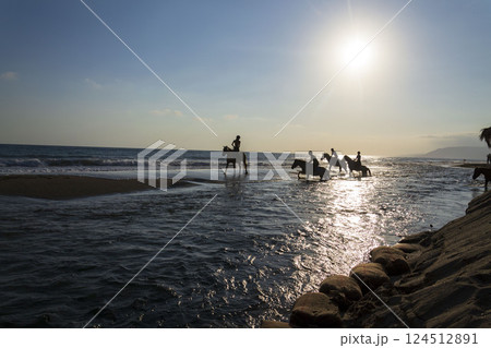 Unrecognizable people riding horses on the beach at dawn, Crete, Greece 124512891