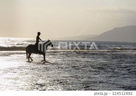 Unrecognizable people riding horses on the beach at dawn, Crete, Greece Unrecognizable people riding horses on the beach at dawn, Crete, Greece 124512892