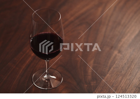 Red wine in thin wine glass on wood table 124513320