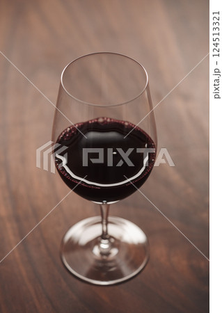 Red wine in wineglass on black walnut table 124513321