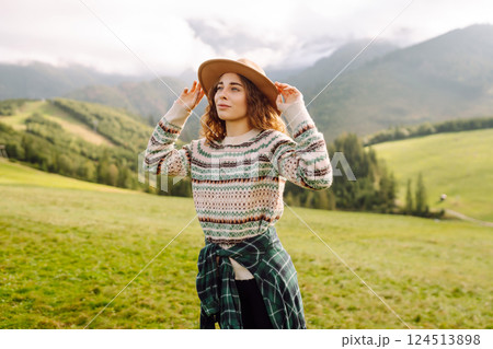 Cute traveler in hat takes selfie against backdrop of green mountain landscapes. Concept of freedom 124513898