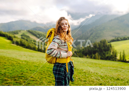 Cute traveler in hat takes selfie against backdrop of green mountain landscapes. Concept of freedom 124513900