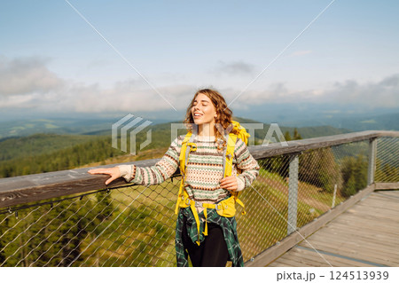 Young woman traveler walking across bridge in middle of forest. Travel and active lifestyle concept. Young woman traveler walking across bridge in middle of forest. Travel and active lifestyle concept. 124513939