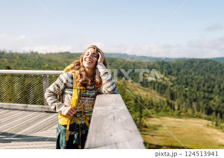 Young woman traveler walking across bridge in middle of forest. Travel and active lifestyle concept. Young woman traveler walking across bridge in middle of forest. Travel and active lifestyle concept. 124513941