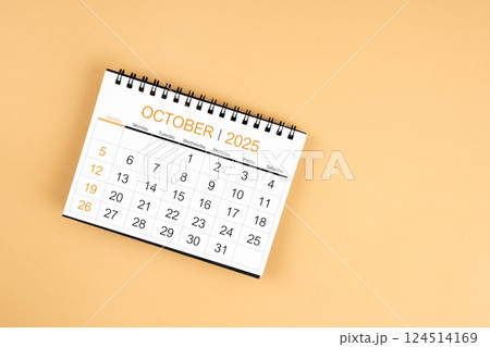 Top view of October 2025 desk calendar on yellow pastel background. 124514169