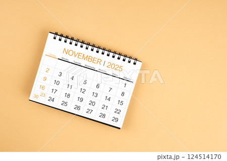 Top view of November 2025 desk calendar on yellow pastel background. 124514170