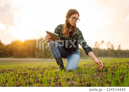 Farmer woman in boots checks the quality of the soil before sowing in her hands with digital tablet. 124514485