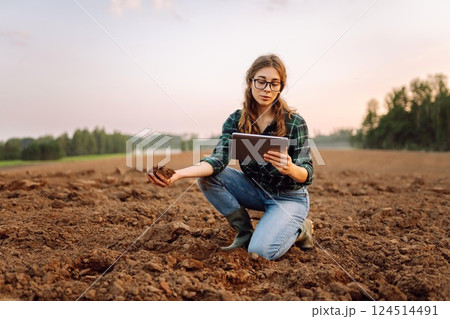 Young woman agronomist checks the quality of the soil before sowing. Concept of technology, ecology. Young woman agronomist checks the quality of the soil before sowing. Concept of technology, ecology. 124514491