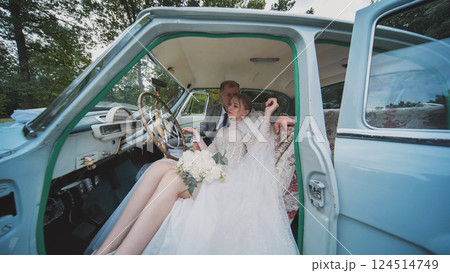 Bride and groom sharing an intimate moment inside a classic car, celebrating their wedding day with romance and style 124514749