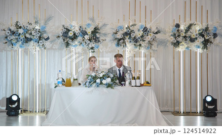 Newlyweds sharing intimate moment at decorated wedding table, surrounded by delicate flowers during romantic reception celebration 124514922