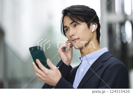 イヤホンをしてスマホを持ったアラサーの男性 イヤホンをしてスマホを持ったアラサーの男性 124515420