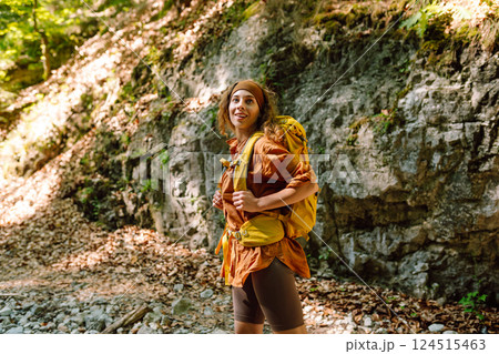 Traveler woman walking along hiking trail through forest thicket in the mountains. Active lifestyle. 124515463