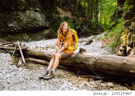 Traveler woman walking along hiking trail through forest thicket in the mountains. Active lifestyle. 124515467