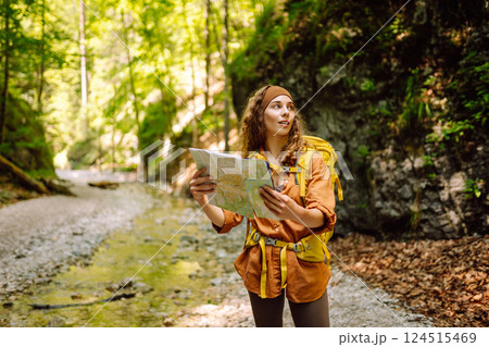 Young woman on a mountain path with a map in her hands, exploring hiking trails. Adventure concept. Young woman on a mountain path with a map in her hands, exploring hiking trails. Adventure concept. 124515469