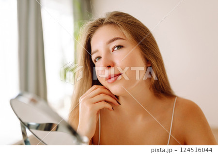 A beautiful woman looking in mirror, examines acne, pigmentation. Cosmetic care. Allergic reaction. 124516044