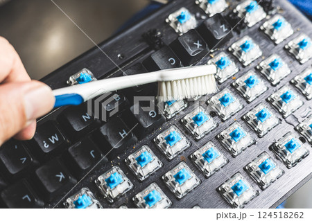 Closeup using old tooth brush cleaning dirty dusty computer keyboard Closeup using old tooth brush cleaning dirty dusty computer keyboard 124518262