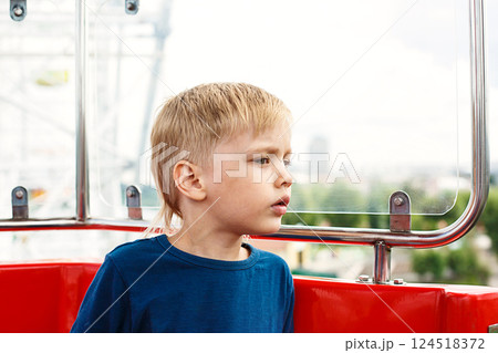 Young Boy Sitting in Amusement Park Attraction Enjoying View for Fun Activity. Summer Adventure, Vacation and Travelling. 124518372
