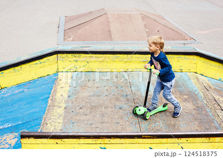 Boy with Kick Scooter Having Fun in Skatepark. Child Making Stunts Enjoying Outdoor Activities. 124518375