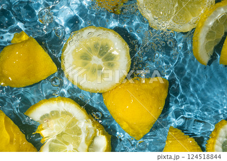 Juicy lemon background of halves and slices of fresh lemons in water. 124518844