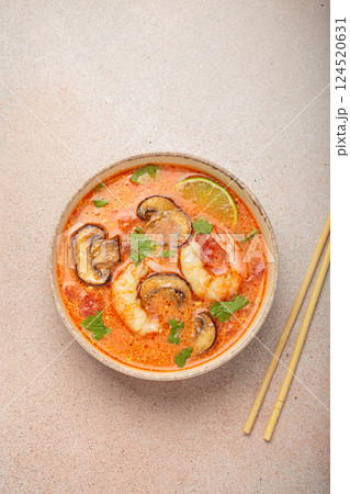Tom yum soup with shrimp and mushrooms in bowl with chopsticks top view, traditional Thai soup 124520631