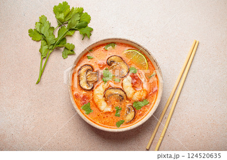 Tom yum soup with shrimp and mushrooms in bowl with chopsticks top view, traditional Thai soup 124520635