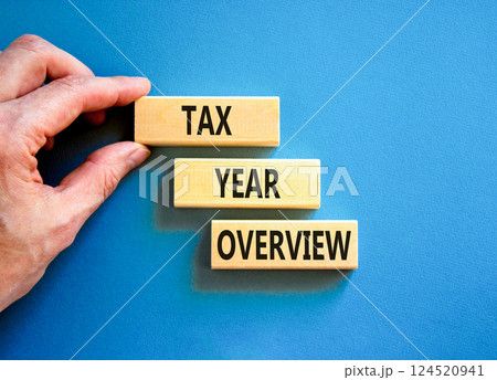 Tax year overview symbol. Concept words Tax year overview on beautiful wooden blocks. Beautiful blue background. Businessman hand. Business tax year overview concept. Copy space. Tax year overview symbol. Concept words Tax year overview on beautiful wooden blocks. Beautiful blue background. Businessman hand. Business tax year overview concept. Copy space. 124520941