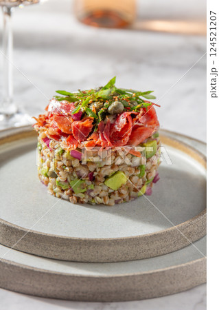 Superfood buckwheat tartare with avocado, capers and red onion, topped with serrano jamon slices 124521207