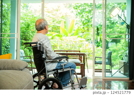 Asian senior man disabled sitting alone near window in wheelchair looking out window at hospital room and thinking, lonely elder sad old man look outside windows, feel depressed 124521779
