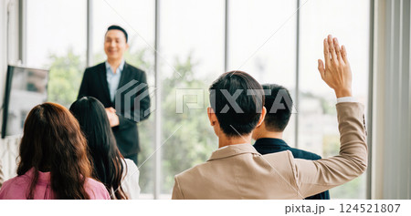 A group of professionals in a seminar meeting room raises their hands to ask questions, symbolizing an engaged audience ready to interact and learn. It's all about the concept of active participation. 124521807