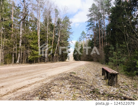 Lonely bench on a dirt road in the woods. Forest dirt road. Lonely bench on a dirt road in the woods. Forest dirt road. 124522079