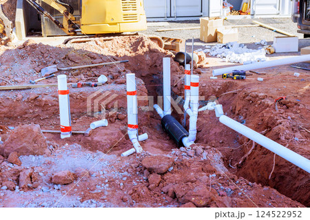 Worker are installing drainage system in residential area with tools excavator equipment nearby. 124522952