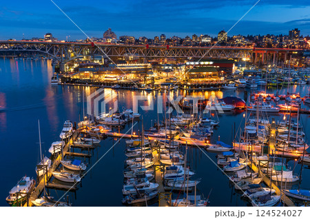 Vancouver, Canada - MAR 11 2021 : Granville Island Marina and Fishermen's Wharf Float at night. Vancouver city buildings skyline and Granville Bridge in the background. 124524027