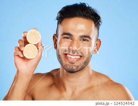 Health, lemon and skincare for man with citrus fruit for facial, vitamin c and wellness with a smile on blue background. Dermatology, beauty and healthy food portrait for clean, glow and skin healthy Health, lemon and skincare for man with citrus fruit for facial, vitamin c and wellness with a smile on blue background. Dermatology, beauty and healthy food portrait for clean, glow and skin healthy 124524542