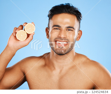 Face, skincare and orange with a man model in studio on a blue background to promote natural beauty. Portrait, fruit and wellness with a handsome young male posing for a health product or treatment Face, skincare and orange with a man model in studio on a blue background to promote natural beauty. Portrait, fruit and wellness with a handsome young male posing for a health product or treatment 124524634