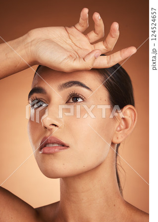 Hand, face and beauty with a model woman in studio on a beige background to promote natural care. Skincare, cosmetics and treatment with an attractive young female posing for a skin product 124524657