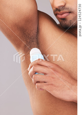 Deodorant, health and man cleaning armpit for wellness, skin and care for body against a grey studio background. Grooming, hygiene and underarm of a person with a product to clean and stop sweat 124524730