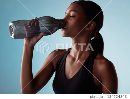 Fitness, sports and woman drinking water in studio for a healthy body after training, cardio workout and exercise. Wellness, blue background and thirsty girl enjoys a beverage to hydrate or hydration Fitness, sports and woman drinking water in studio for a healthy body after training, cardio workout and exercise. Wellness, blue background and thirsty girl enjoys a beverage to hydrate or hydration 124524848