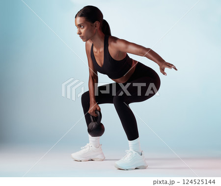 Black woman, kettlebell and exercise for wellness, focus or motivation for health, fitness and studio background. Female trainer, training and athlete being healthy for workout, strong and sportswear 124525144