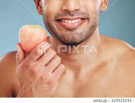 Face, skincare and man with apple for health, vitamin c and nutrition on blue studio background. Wellness, healthy lifestyle or bearded model holding fruit for minerals, natural skin or facial care 124525245