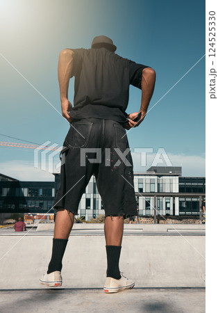 Skate clothes, urban fashion and man with emo, goth or gen z contemporary street style at fitness skate park for training. Blue sky lens flare, concrete building and back view of stylish black person Skate clothes, urban fashion and man with emo, goth or gen z contemporary street style at fitness skate park for training. Blue sky lens flare, concrete building and back view of stylish black person 124525330