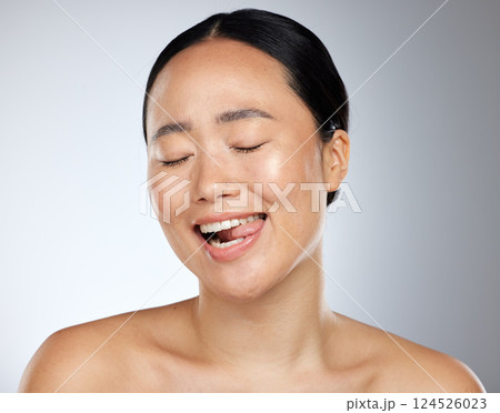 Woman face, tongue out and beauty skincare natural makeup glow. Young happy Asian girl, funny face eyes closed and healthy facial or body cosmetics for advertisement in grey studio background 124526023