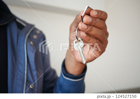 Man holding keys indoors in a casual setting while smiling 124527150