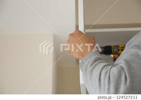 Person assembling furniture with power drill in modern interior 124527211