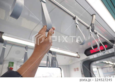 Commuter holds safety strap on urban transit train interior Commuter holds safety strap on urban transit train interior 124527245