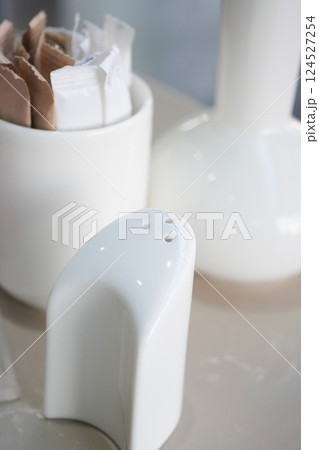 Simple white salt shaker and sugar packets on a table Simple white salt shaker and sugar packets on a table 124527254