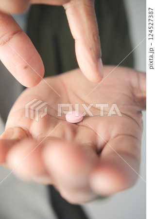Hand holding a pink tablet in a thoughtful moment Hand holding a pink tablet in a thoughtful moment 124527387