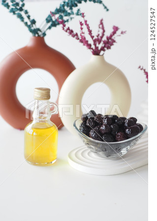 Olive oil and black olives on a table with vases and decor Olive oil and black olives on a table with vases and decor 124527547